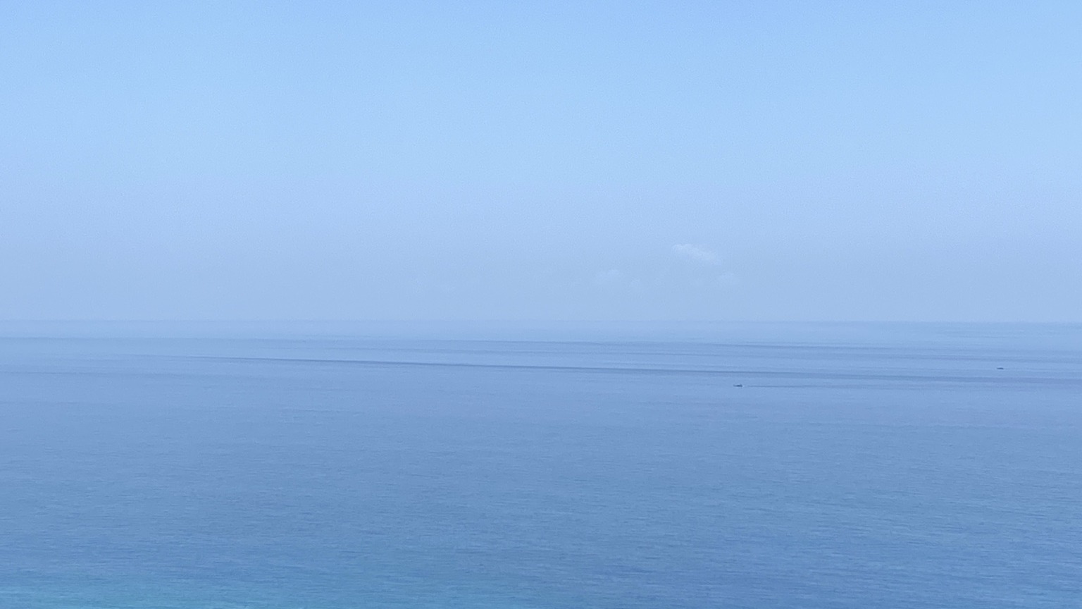 霧藍天空、清楚的海平線與平靜海面